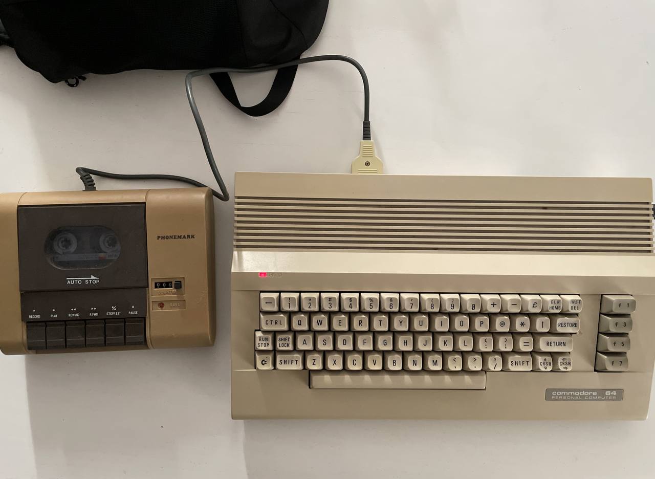 a commodore c64c on a white table with a datasette connected to it